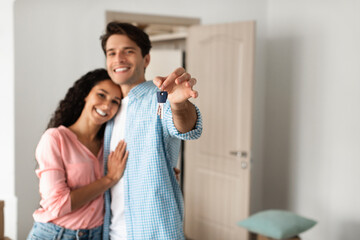 Happy man and woman posing with keys on moving day