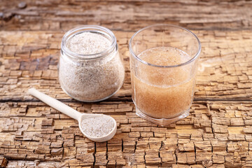 psyllium capsules and a glass of water and psyllium husk on an old wooden board