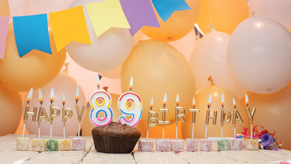 Happy birthday greetings for 89 years from gold letters of candles burning against the background of mine space balloons. Beautiful birthday card with a muffin for eighty-nine years.