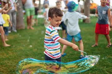 the child inflates large soap bubbles. Street animation program, happy child on a green lawn....