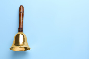 Golden school bell with wooden handle on light blue background, top view. Space for text