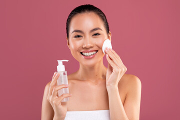 Attractive japanese woman cleansing her skin, using toner