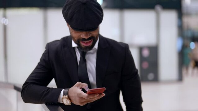 stylish black man is using smartphone, checking new app, viewing social media
