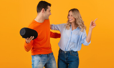 attractive stylish young couple holding wireless speaker