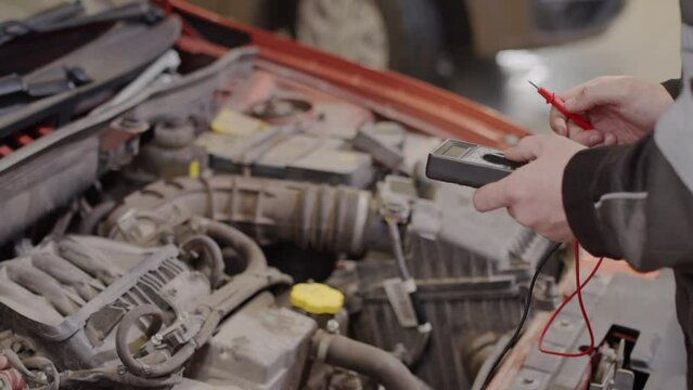 Close up view of hands of mechanic using car code reader while doing vehicle diagnostics in auto service shop