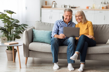 Cheerful Senior Spouses Using Laptop Watching Movie Onilne At Home