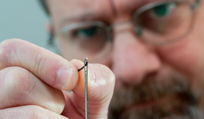 man threads a needle