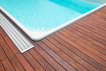 Teak hardwood decking installed around the blue swimming pool