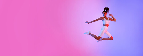 Athletic Lady Jumping Posing In Mid-Air Exercising Over Neon Background