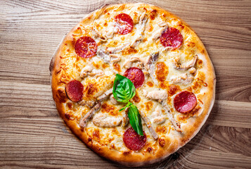 Pizza with Mozzarella cheese, salami, ham, Tomato sauce, pepper, spices. Italian pizza on wooden background