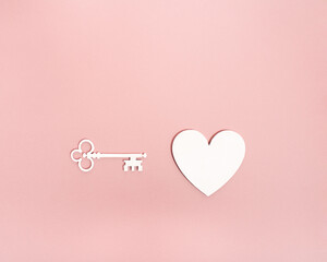 A beautiful white key turned towards the pure heart shape on pastel pink background with copy space for commercial. Minimal freedom concept for romantic valentine holiday. Find the way to your heart.