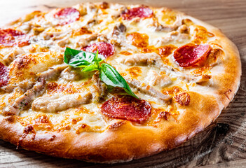 Pizza with Mozzarella cheese, salami, ham, Tomato sauce, pepper, spices. Italian pizza on wooden background