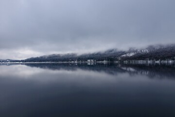 Bohinj lake in Slovenia in winter with low level clouds above the lake and reflection in the lake