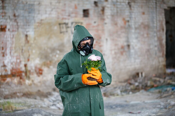 Obraz premium A dosimetrist scientist radiation inspector in protective clothing and a gas mask examines the danger zone. Close-up. Flower. Ecological catastrophy