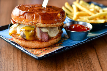 Delicious Beef  Burger  with bacon, cheddar ,egg  and home made french fries from organic potatoes on wooden table 
