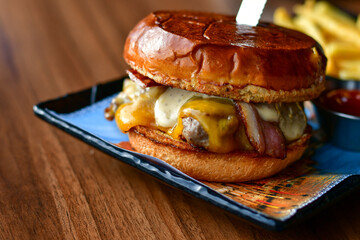 Delicious Beef  Burger  with bacon, cheddar ,egg  and home made french fries from organic potatoes on wooden table 