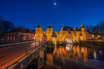 Fototapeta na wymiar An old medieval gate called the Koppelpoort in Amersfoort with a beautiful reflection and traffic lights during the blue hour