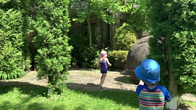 Cute Happy Kid Little Preschool Baby Girl and Boy Child Play Have Fun with Water Pump Gun Outside. Sunny Hot Nice Day in Park. Children Backyard Garden Games. Summer, Sport, Holiday, Family, Childhood