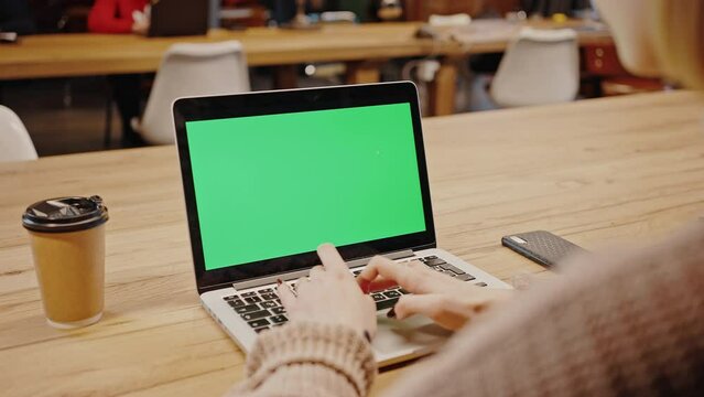 Close up shot of laptop with green chroma key screen, unrecognizable woman student typing online at library