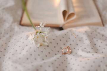 Fototapeta na wymiar Wedding golden ring and open book with folded sheets in heart shape in bed. Wedding concept, Happy Valentine's Day