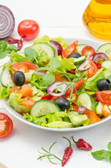 Healthy fresh vegetable salad with tomatoes, cucumbers and bell peppers in a plate on a white wooden background