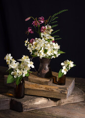 Still life with bouquets of jasmine flowers and with an orchid on an vintage wooden table on a black background