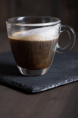 Cafe espresso macchiato layered coffee in a see through glass coffee cup.