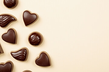Chocolate pralines on beige background, flat lay, top view with copy space