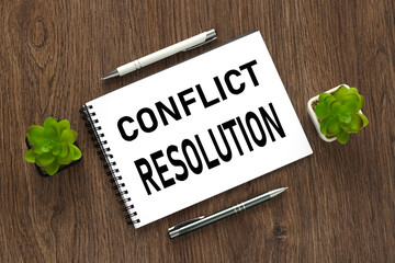 CONFLICT RESOLUTION open notepad with text. on a wooden background. business concept