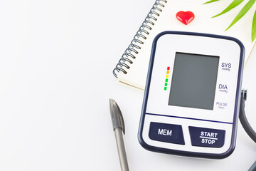 Digital blood pressure monitor, notepad, pen on a white background with copy space. The concept of...