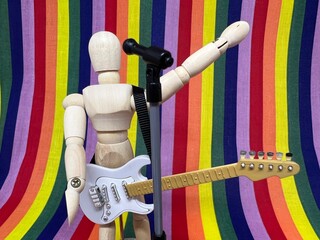レインボーの背景の前でギターを下げて拳を上げて歌うシンガー。LGBT・同性愛のミュージシャンのイメージ。