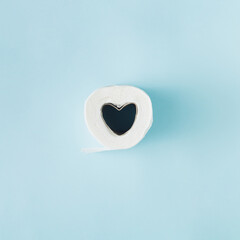 Toilet paper with a heart in a row on a blue background. Minimal love flatlay