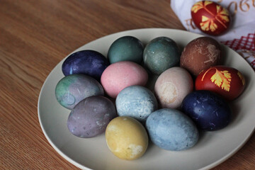 Easter eggs painted with natural paints in a plate on dish on wooden background. colorful Easter eggs in ceramic dish on wooden background.