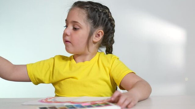 Child girl drawing a rainbow. child artist draws at the table in kindergarten. coronavirus pandemic indoor stay home concept. kid draws a rainbow. school kindergarten drawing lesson