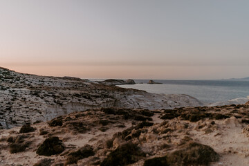 The sandstone white rocks cliffs moonscape of Sarakiniki volcanic beach in Milos Island Greece surrounded by turquoise blue waves and sea at sunset