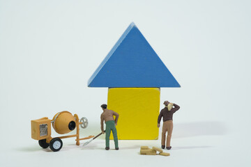 a team of workers with a cement mixer is working on a yellow house with a blue roof, white...