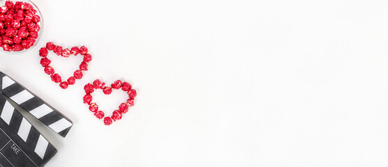 Valentine's Day movie concept. Clapperboard with hearts made of red caramel popcorn with copy space