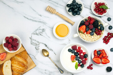 Fototapeta na wymiar Healthy breakfast with yogurt of fruit, oat with berry, honey and ripe sweet berries on white marble background top wave, flat lay.