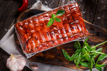 Meat delicacy, baked boiled pork, whole or sliced on a kitchen cutting board, spices and...