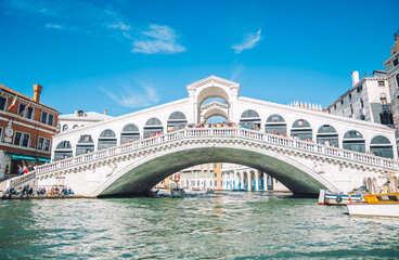 Fototapeta na wymiar Scenery view on district with vintage buildings and urban setting with old historic architecture, selective focus on famous bridge in Venice - called Rialto Bridge must have for visiting on vacations
