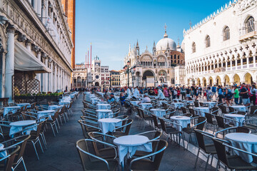 Fototapeta na wymiar Ancient square of San Marco located in historic center of venice with ancient cathedral basilicas and architecture buildings for visiting during summer travel vacations, table of street cafe for rest