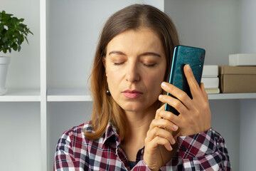 Blind woman holding mobile phone using speakerphone.