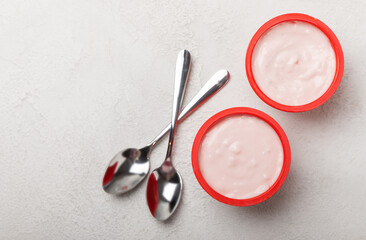 strawberry yogurt in a red plastic cup with a spoon on a white background.
Copy space.