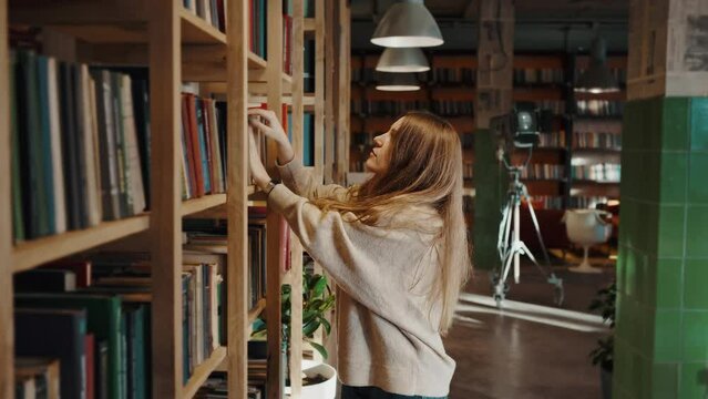 Young woman putting uninteresting book on shelf and choosing another, searching for literature to read, slow motion