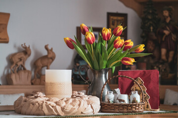 table decoration with a flower vase with colorful tulips and a candle in a carved wood ring