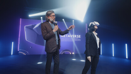Two speakers in virtual reality glasses standing on the stage and talking about modern technologies...