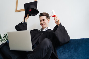 Education, graduation and people concept - happy male student with diploma and laptop at home showing his emotions