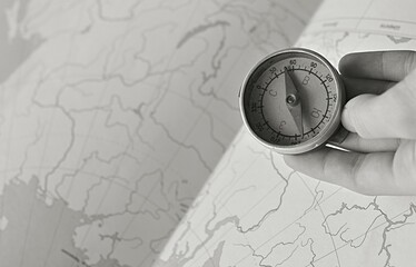 hand holding a compass on the background of a contour map