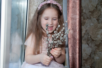 a little girl holds a willow in her hands for Easter rejoicing with a wide smile
