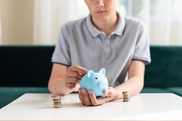 Kid teen boy saving money putting coins in a piggy bank. Learning financial responsibility and projecting savings. The concept of saving money, finance, business and investment, Lessons in mindfulness